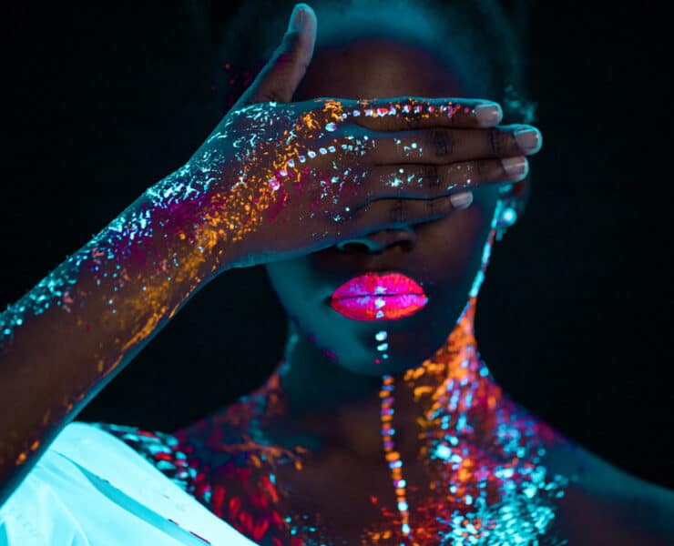 Woman wearing UV paint, hiding her eyes