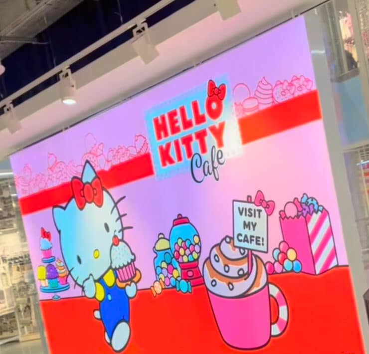hello kitty cafe sign - hello kitty is holding a cupcake with lots of sweet treats around her