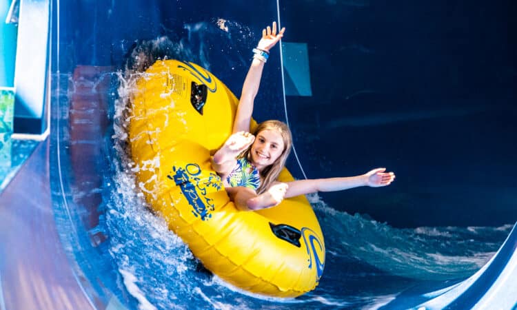 girl in a round dingie going down a slide
