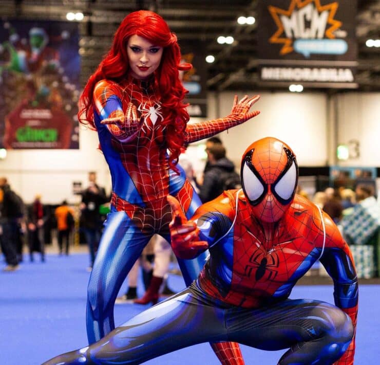 woman dressed as spider woman standing and man dressed as spider man crouching