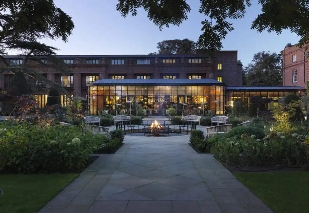 The Grove hotel lit up at night with outdoor seating and a fire pit