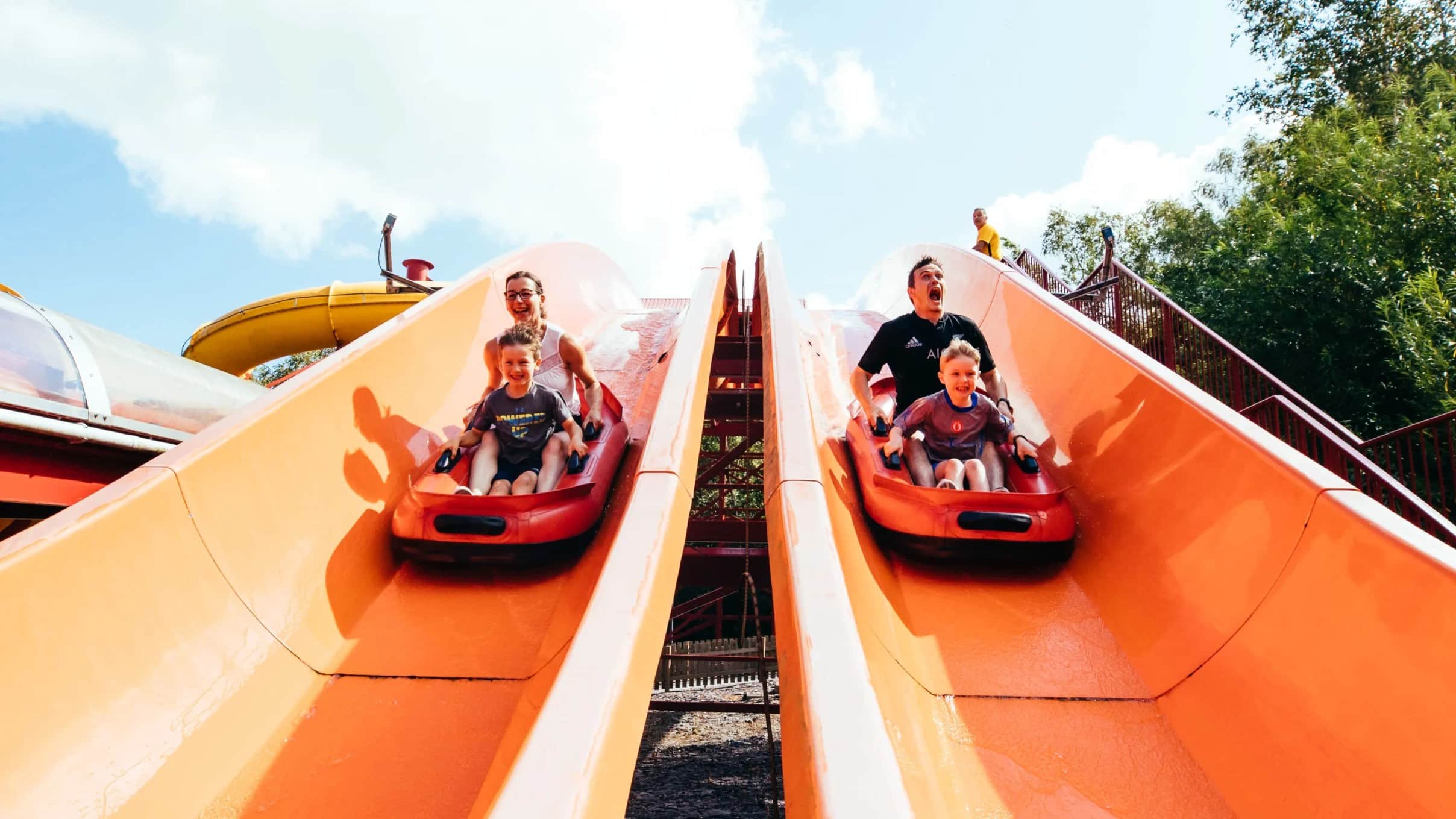 giant orange slide with two people going down on sleds