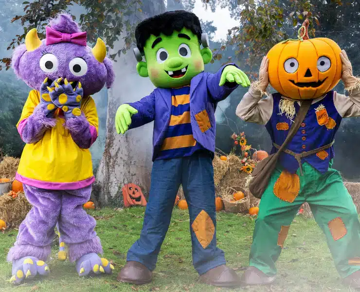 Three costumed Halloween characters, including a purple monster, a green Frankenstein's monster, and a pumpkin-headed